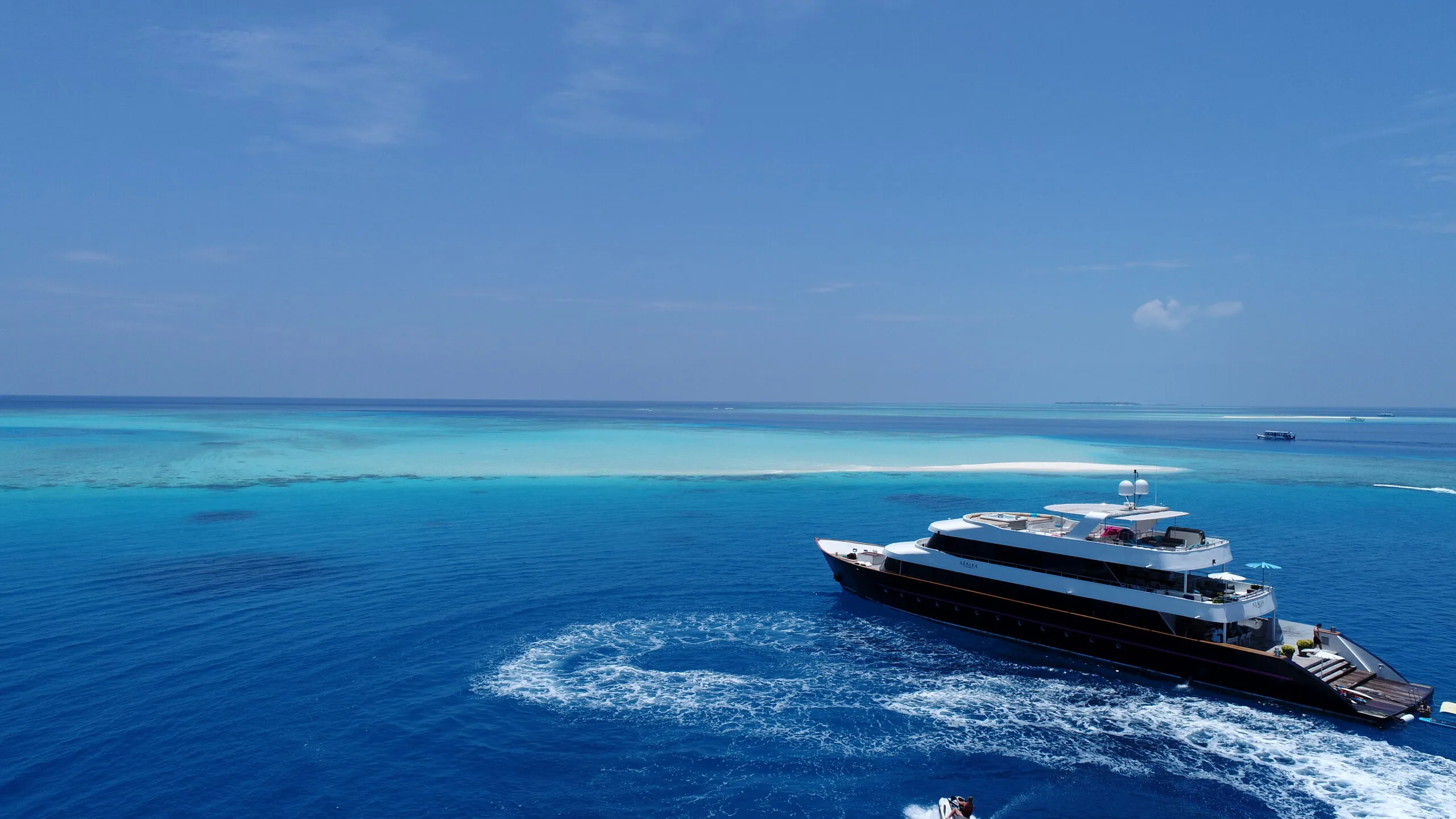 Aerial view of AZALEA yacht over coral reefs in the Maldives.
